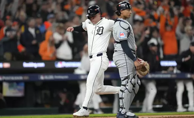 Detroit Tigers' Kerry Carpenter, left, scores in front of Cleveland Guardians catcher Bo Naylor in the sixth inning during Game 4 of a baseball American League Division Series, Thursday, Oct. 10, 2024, in Detroit. (AP Photo/Paul Sancya)