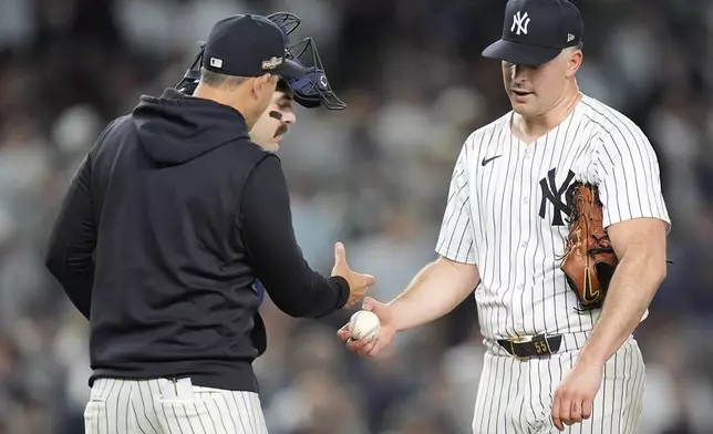 New York Yankees pitcher Carlos Rodón hands the ball to manager Aaron Boone as he leaves the game during the fourth inning of Game 2 of the American League baseball playoff series against the Kansas City Royals, Monday, Oct. 7, 2024, in New York. (AP Photo/Frank Franklin II)