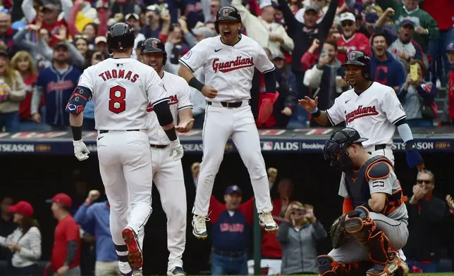 Cleveland Guardians players, from rear left, David Fry, Steven Kwan and Jose Ramirez greet teammate Lane Thomas after Thomas hit a grand slam in the fifth inning during Game 5 of baseball's American League Division Series against the Detroit Tigers, Saturday, Oct. 12, 2024, in Cleveland. Tigers catcher Jake Rogers is at right. (AP Photo/Phil Long)