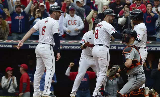 Cleveland Guardians' Lane Thomas (8) celebrates with teammates, from left, David Fry, Steven Kwan, partially hidden, and Jose Ramirez, right, behind Detroit Tigers catcher Jake Rogers, after hitting a grand slam in the fifth inning during Game 5 of baseball's American League Division Series, Saturday, Oct. 12, 2024, in Cleveland. (AP Photo/Phil Long)