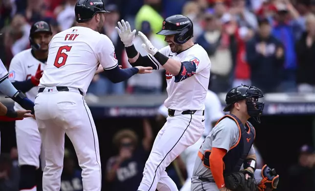 Cleveland Guardians' Lane Thomas, center, is greeted by teammate David Fry, left, behind Detroit Tigers catcher Jake Rogers, right, after hitting a grand slam in the fifth inning during Game 5 of baseball's American League Division Series, Saturday, Oct. 12, 2024, in Cleveland. (AP Photo/David Dermer)