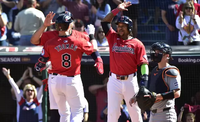 Cleveland Guardians' Lane Thomas (8) is greeted at the plate by teammates Josh Naylor, rear and third baseman Jose Ramirez, second right, in front of Detroit Tigers catcher Jake Rogers, right, after hitting a home run in the first inning during Game 1 of baseball's AL Division Series, Saturday, Oct. 5, 2024, in Cleveland. (AP Photo/Phil Long)