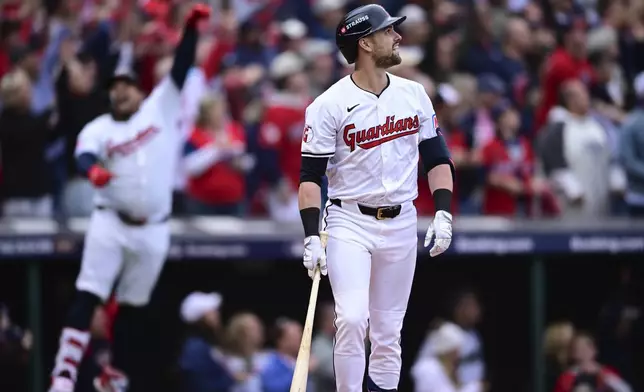 Cleveland Guardians' Lane Thomas, right, watches his grand slam in the fifth inning during Game 5 of baseball's American League Division Series against the Detroit Tigers, Saturday, Oct. 12, 2024, in Cleveland. (AP Photo/David Dermer)