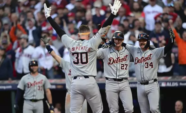 Detroit Tigers' Trey Sweeney (27) and Jake Rogers wait at home plate for teammate Kerry Carpenter after Carpenter hit a three-run home run in the ninth inning during Game 2 of baseball's AL Division Series against the Cleveland Guardians, Monday, Oct. 7, 2024, in Cleveland. (AP Photo/David Dermer)