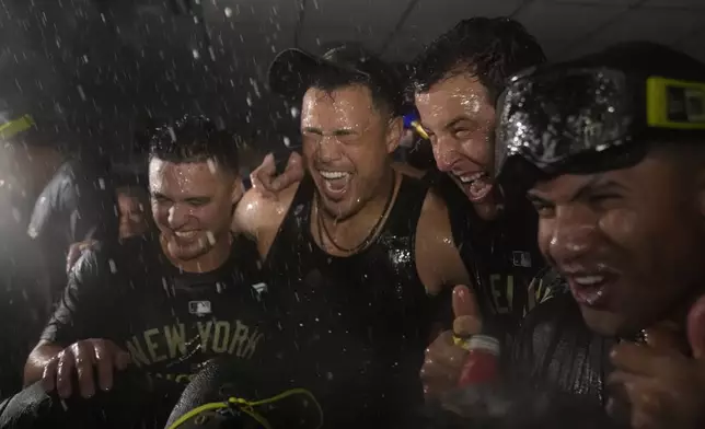 Members of the New York Yankees celebrate in the clubhouse following a 3-1 victory over the Kansas City Royals in Game 4 of an American League Division baseball playoff series Thursday, Oct. 10, 2024, in Kansas City, Mo. (AP Photo/Charlie Riedel)