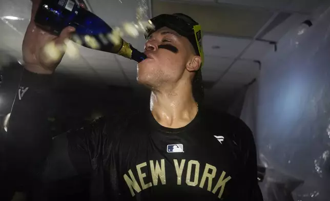 New York Yankees' Aaron Judge celebrates in the clubhouse following a 3-1 victory over the Kansas City Royals in Game 4 of an American League Division baseball playoff series Thursday, Oct. 10, 2024, in Kansas City, Mo. (AP Photo/Reed Hoffmann)