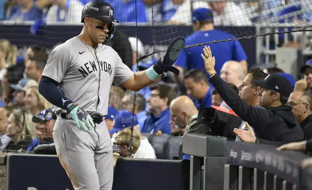 New York Yankees' Aaron Judge is congratulated by teammates after scoring during the sixth inning in Game 4 of an American League Division baseball playoff series against the Kansas City Royals Thursday, Oct. 10, 2024, in Kansas City, Mo. (AP Photo/Reed Hoffmann)