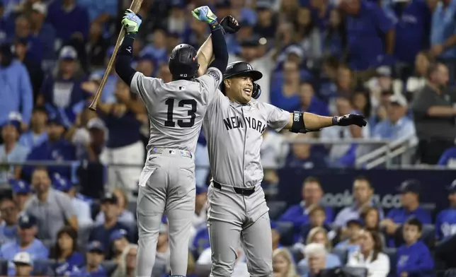 New York Yankees' Giancarlo Stanton is congratulated by teammate Jazz Chisholm Jr. (13) after hitting a solo home run during the eighth inning in Game 3 of an American League Division baseball playoff series against the Kansas City Royals Wednesday, Oct. 9, 2024, in Kansas City, Mo. (AP Photo/Colin Braley)