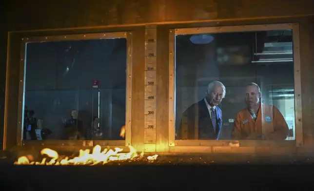 Britain's King Charles III listens to research scientist Dr. Matt Plucinski, right, describe the "Pyrotron" combustion wind tunnel during a visit to the CSIRO National Bushfire Behaviour Research Laboratory in Canberra, Monday, Oct. 21, 2024. (AP Photo/Tracey Nearmy, Pool)