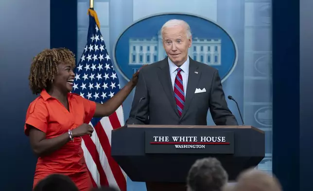 President Joe Biden stands next to White House press secretary Karine Jean-Pierre when Biden made a surprise appearance during the daily briefing at the White House in Washington, Friday, Oct. 4, 2024. (AP Photo/Ben Curtis)