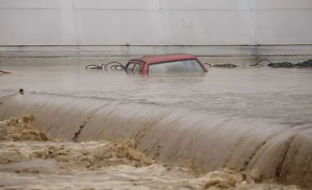 A car is submerged in flood waters outside an apartment building in the village of Kiseljak, northern Bosnia, Friday, Oct. 4, 2024. (AP Photo/Armin Durgut)