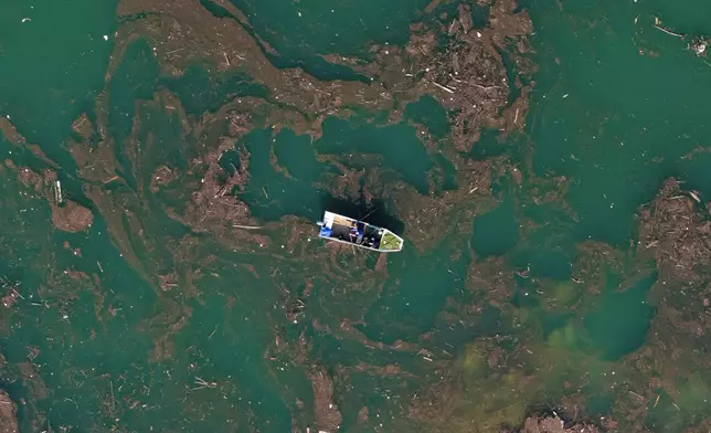 Aerial view of Ibro Mesic rowing his boat through mud and waste after devastating floods and landslides put tons of waste in Jablanicko lake near Ostrozac, Bosnia, Sunday, Oct. 20, 2024. (AP Photo/Armin Durgut)