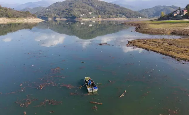 Aerial view of Ibro Mesic rowing his boat through mud and waste after devastating floods and landslides put tons of waste in Jablanicko lake near Ostrozac, Bosnia, Sunday, Oct. 20, 2024. (AP Photo/Armin Durgut)