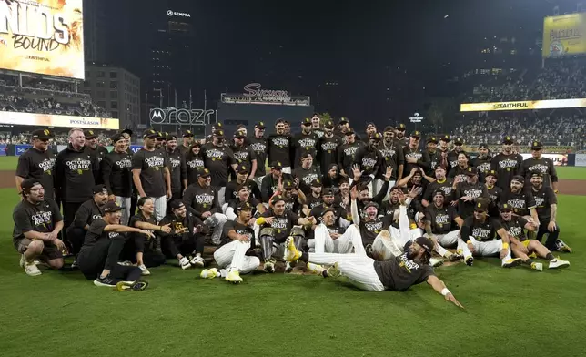 San Diego Padres' Fernando Tatis Jr., bottom, center, slides in to join a group photo after the Padres beat the Atlanta Braves in Game 2 of an NL Wild Card Series baseball game Wednesday, Oct. 2, 2024, in San Diego. (AP Photo/Gregory Bull)