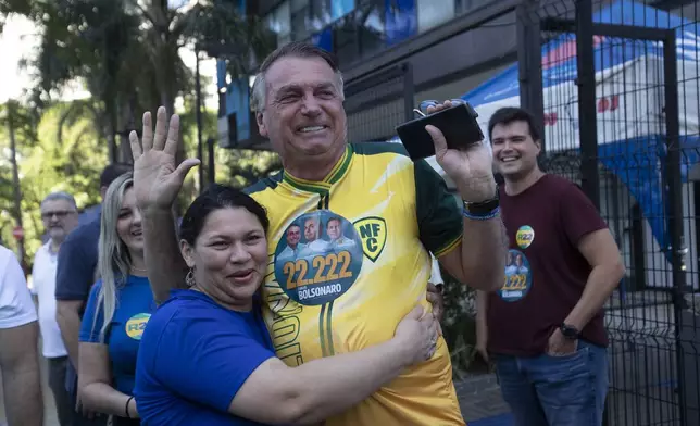 A supporter hugs former Brazilian President Jair Bolsonaro, center, as he supports for Rio de Janeiro mayoral candidate Alexandre Ramagem during municipal elections in Rio de Janeiro, Sunday, Oct. 6, 2024. (AP Photo/Bruna Prado)