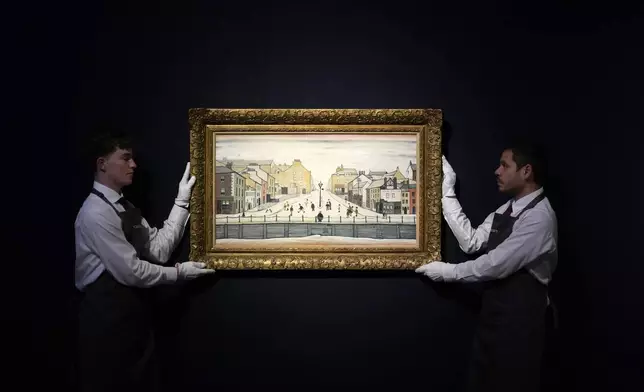 Gallery employees display a painting by Laurence Stephen Lowry called Senhouse, Maryport at Christie's auction rooms in London, Friday, Oct. 11, 2024, the painting estimated at 700,000-1,000,000 UK pounds will be auctioned in the Modern British and Irish Evening Sale on Oct.16.(AP Photo/Kirsty Wigglesworth)