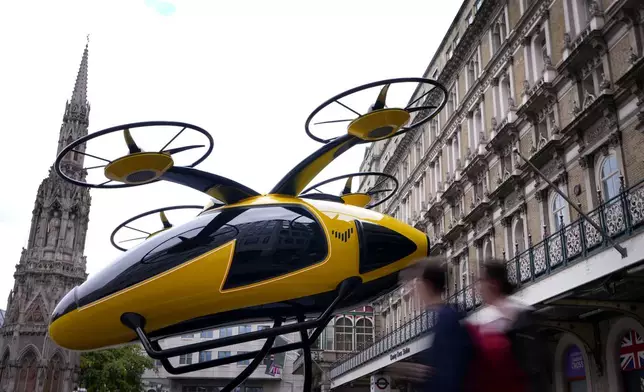 Pedestrians pass a prototype of a flying taxi, which is currently in development in the United Arab Emirates (UAE), after it was unveiled in the taxi rank outside Charing Cross railway station in London, Wednesday, Oct. 9, 2024. (AP Photo/Kirsty Wigglesworth)