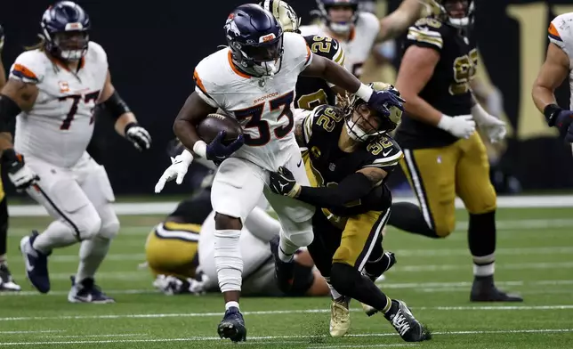 Denver Broncos running back Javonte Williams (33) breaks a tackle by New Orleans Saints safety Tyrann Mathieu (32) during the first half of an NFL football game, Thursday, Oct. 17, 2024, in New Orleans. (AP Photo/Butch Dill)