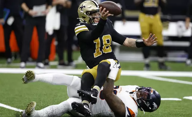 New Orleans Saints quarterback Spencer Rattler (18) is sacked by Denver Broncos defensive end John Franklin-Myers during the second half of an NFL football game, Thursday, Oct. 17, 2024, in New Orleans. (AP Photo/Butch Dill)