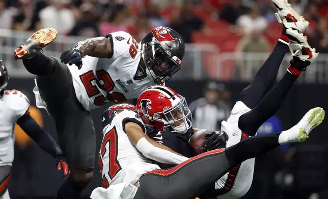 Atlanta Falcons wide receiver Darnell Mooney (1) makes a touchdown reception between Tampa Bay Buccaneers cornerback Zyon McCollum (27) and safety Christian Izien (29) during the first half of an NFL football game Thursday, Oct. 3, 2024, in Atlanta. (AP Photo/Butch Dill)