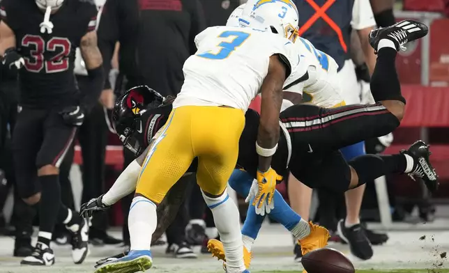 Arizona Cardinals running back James Conner fumbles the ball as he is hit by Los Angeles Chargers safety Derwin James Jr. (3) during the first half of an NFL football game, Monday, Oct. 21, 2024, in Glendale Ariz. The Cardinals recovered the fumble. (AP Photo/Matt York)