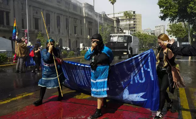 Police fire water and tear gas at Mapuche Indigenous women and supporters during a march to demand autonomous territory for Chile's Indigenous people and the release of pro-Mapuche detainees, in Santiago, Chile, Sunday, Oct. 13, 2024. (AP Photo/Esteban Felix)