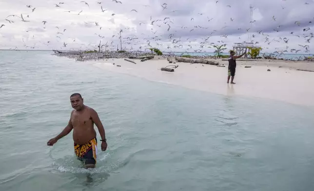 Peter Lorenzo, left, walks to a boat that brought supplies, as Jefferson Nestor, a state legislator with Hatohobei State, takes pictures of the bridled tern on Helen Island, Palau, before returning back to the boat on July 18, 2024. (AP Photo/Yannick Peterhans)