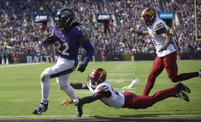 Baltimore Ravens running back Derrick Henry (22) scores past Washington Commanders safety Quan Martin and safety Jeremy Chinn, right, during the first half of an NFL football game Sunday, Oct. 13, 2024, in Baltimore. (AP Photo/Nick Wass)