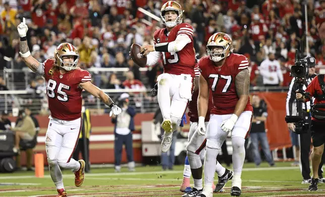 San Francisco 49ers quarterback Brock Purdy, middle, celebrates after scoring a touchdown with tight end George Kittle (85) and guard Dominick Puni (77) during the second half of an NFL football game against the Dallas Cowboys in Santa Clara, Calif., Sunday, Oct. 27, 2024. (AP Photo/Eakin Howard)