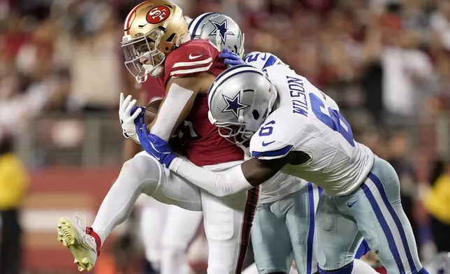 San Francisco 49ers running back Isaac Guerendo, left, runs against Dallas Cowboys safety Donovan Wilson (6) and cornerback Jourdan Lewis, rear, during the first half of an NFL football game in Santa Clara, Calif., Sunday, Oct. 27, 2024. (AP Photo/Tony Avelar)