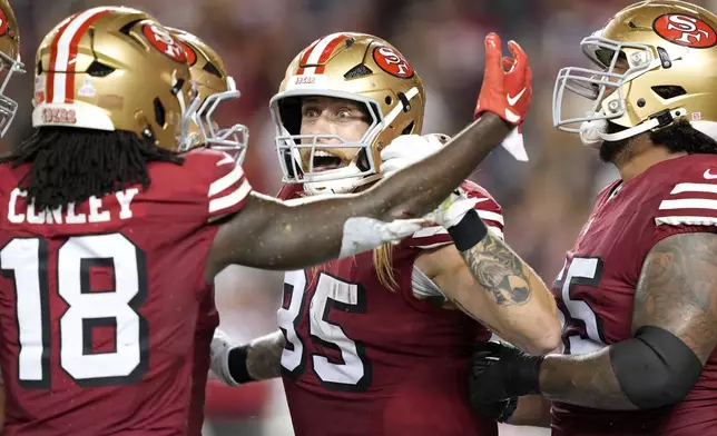 San Francisco 49ers tight end George Kittle, middle, is congratulated by wide receiver Chris Conley (18) and teammates after catching a touchdown pass against the Dallas Cowboys during the second half of an NFL football game in Santa Clara, Calif., Sunday, Oct. 27, 2024. (AP Photo/Tony Avelar)