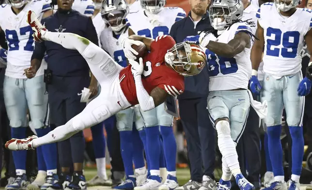 San Francisco 49ers cornerback Deommodore Lenoir, foreground left, intercepts a pass intended for Dallas Cowboys wide receiver CeeDee Lamb (88) during the second half of an NFL football game in Santa Clara, Calif., Sunday, Oct. 27, 2024. (AP Photo/Eakin Howard)