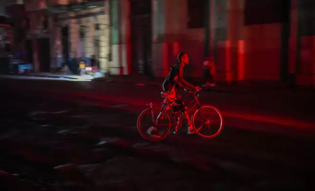 A resident walks his bicycle during a blackout following the failure of a major power plant in Havana, Cuba, Sunday, Oct. 20, 2024. (AP Photo/Ramon Espinosa)