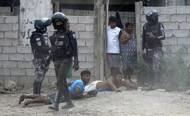 Residents lie on the ground as military and police officers raid a home as part of a joint operation searching for weapons and drugs in a neighborhood of Guayaquil, Ecuador, Wednesday, Oct. 16, 2024. (AP Photo/Cesar Munoz)