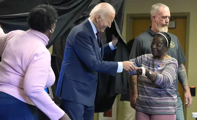 President Joe Biden is handed an "I Voted Early" sticker upon exiting the voting booth after casting his early-voting ballot for the 2024 general elections, Monday, Oct. 28, 2024, in New Castle, Del. (AP Photo/Manuel Balce Ceneta)