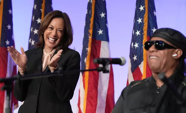 Democratic presidential nominee Vice President Kamala Harris listens as Stevie Wonder performs "Redemption Song" during a church service and early vote event at Divine Faith Ministries International, Sunday, Oct. 20, 2024, in Jonesboro, Ga. (AP Photo/Jacquelyn Martin)