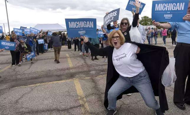 Supporters of Democratic presidential nominee Vice President Kamala Harris, including Carrie Charlick in the white shirt at right, cheer with members of the Harris campaign staff as they line up to enter the Dort Financial Center for a rally in Flint, Mich., Friday, Oct. 4, 2024. (AP Photo/Carolyn Kaster)