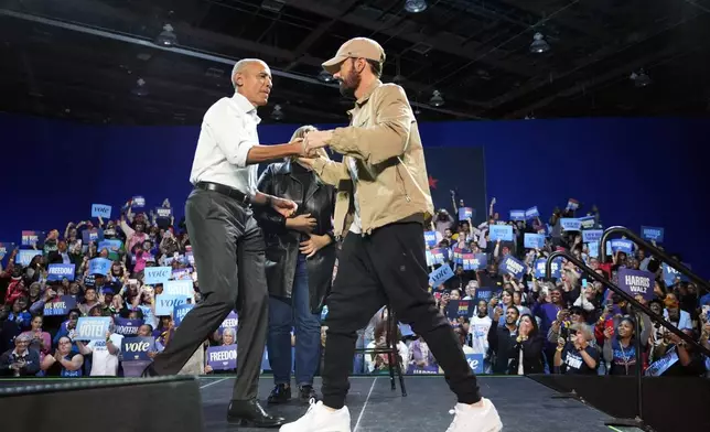 Rapper Eminem, right, greets former President Barack Obama, left, on stage at a campaign rally supporting Democratic presidential nominee Vice President Kamala Harris, Tuesday, Oct. 22, 2024, in Detroit. (AP Photo/Paul Sancya)