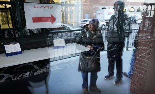 Judy Hemingson, left, of Des Moines, Iowa, waits in line for early voting at the Polk County Election Office, Wednesday, Oct. 16, 2024, in Des Moines, Iowa. (AP Photo/Charlie Neibergall)