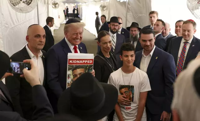 Republican presidential nominee former President Donald Trump poses for photos with family members of Edan Alexander, a hostage held by Hamas, after visiting the gravesite of Rabbi Menachem Mendel Schneerson, Monday, Oct. 7, 2024, in New York. (AP Photo/Yuki Iwamura)