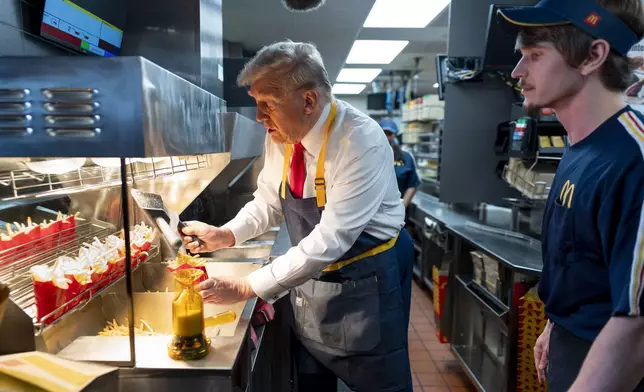 Republican presidential nominee former President Donald Trump, left, uses a frier as an employee looks on during a visit to McDonald's in Feasterville-Trevose, Pa., Sunday, Oct. 20, 2024. (Doug Mills/The New York Times via AP, Pool)