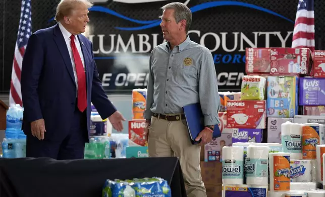 Republican presidential nominee former President Donald Trump talks with Georgia Gov. Brian Kemp after speaking at a temporary relief shelter as he visits areas impacted by Hurricane Helene, Friday, Oct. 4, 2024, in Evans, Ga. (AP Photo/Evan Vucci)