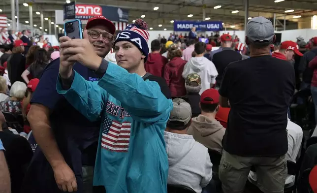 Supporters take a photo as Republican presidential nominee former President Donald Trump speaks at a campaign event at Dane Manufacturing, Tuesday, Oct. 1, 2024, in Waunakee, Wis. (AP Photo/Charlie Neibergall)