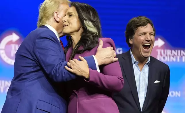 Former Democratic Rep. Tulsi Gabbard hugs Republican presidential nominee former President Donald Trump as Tucker Carlson yells during a campaign rally Wednesday, Oct. 23, 2024, in Duluth, Ga. (AP Photo/Alex Brandon)