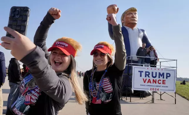 Faith Rail, right, and Kellie Kamphuis take a selfie in front of an inflatable of Republican presidential nominee former President Donald Trump before he speaks at a campaign stop at the Dodge County Airport Sunday, Oct. 6, 2024, in Juneau, Wis. (AP Photo/Morry Gash)