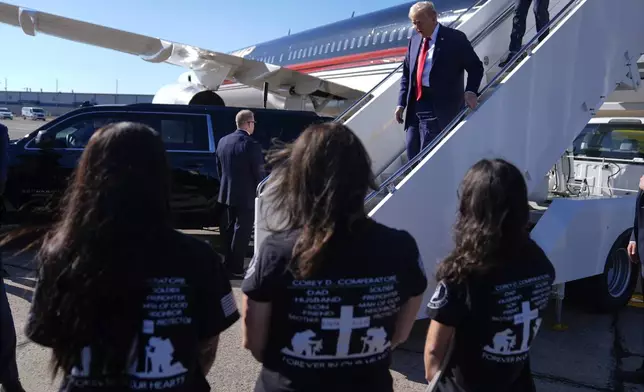 Republican presidential nominee former President Donald Trump arrives as family members of Corey Comperatore wait as he arrives at Pittsburgh International Airport en route to speak at a campaign rally at the Butler Farm Show, Saturday, Oct. 5, 2024, in Pittsburgh. (AP Photo/Evan Vucci)