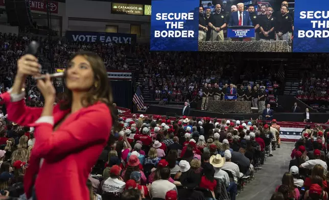 A TV reporter puts on make up while Republican presidential nominee former President Donald Trump delivers a speech during a campaign rally at the Findlay Toyota Arena, Sunday, Oct. 13, 2024, in Prescott Valley, Ariz. (AP Photo/Rodrigo Abd)