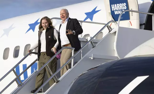 Democratic vice presidential nominee Minnesota Gov. Tim Walz, right, walks off his campaign plane with his daughter, Hope Walz, as they arrives at the Wilkes-Barre/Scranton International Airport in Avoca, Pa., before a campaign event Friday, Oct. 25, 2024. (Christopher Dolan/The Times-Tribune via AP)