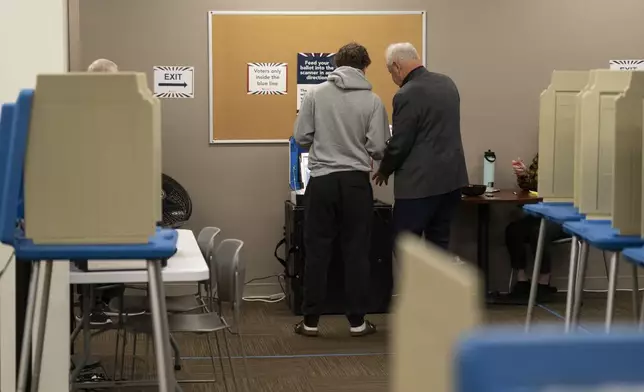 Democratic vice presidential nominee Minnesota Gov. Tim Walz, right, and his son, Gus Walz, a first-time voter, cast their ballots during early voting at the Ramsey County Elections office in St. Paul, Minn., Wednesday, Oct. 23, 2024. (Renée Jones Schneider/Star Tribune via AP, Pool)