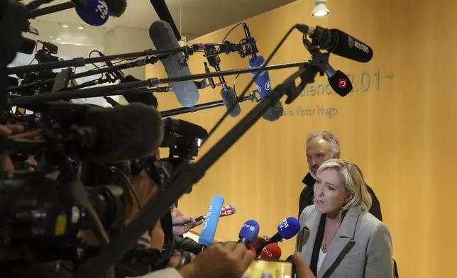 French far-right leader Marine Le Pen, front, speaks to the media as she arrives at the court house in Paris, Monday, Sept. 30, 2024. (AP Photo/Thibault Camus)